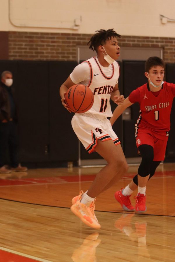 Dribbling along the three-point line, sophomore Sam Dillard looks to pass the ball. On Dec. 10, the Fenton varsity Tigers defeated the Swarts Creek Dragons with a final score of 62-43. 