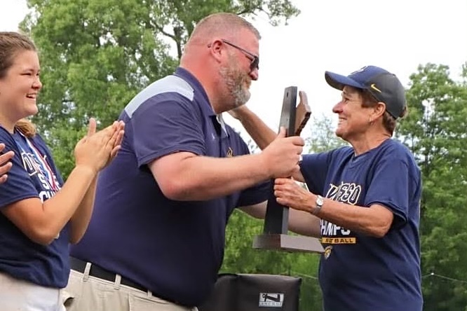New+Interim+Athletic+Director+Dallas+Lintner+presents+the+MHSAA+State+Championship+trophy+to+Owosso+HS+softball+coach+JoEllen+Smith+in+June+of+2021.%0A