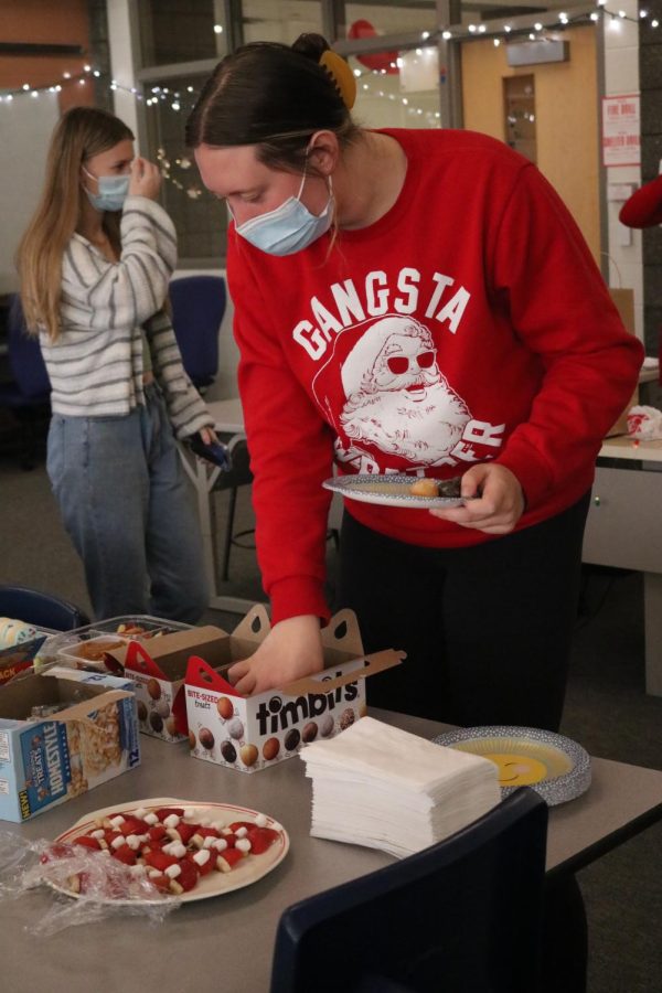 Reaching for donuts, junior Adrie Staib celebrates Christmas by wearing her Christmas sweater. On Dec. 17, the Fentonian threw a party to celebrate the holidays.  