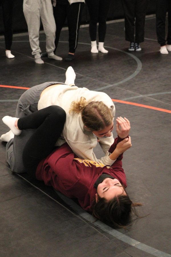  Juniors Sienna Sahr and Lauren Caldwell learn how to defend themselves when someone is on top of them. On Jan. 27, Fenton police officer Tom Cole taught the girls how to defend themselves in Fitness and Conditioing teacher Becki Moores class. 