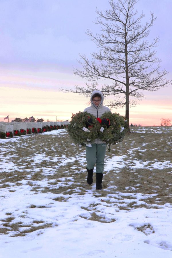 Carrying wreaths, sophomore Naomi Durant walks toward the dumpster. On Jan. 22, Fentons girls basketball program cleaned up wreaths at the Great Lakes National Cemetery that were laid for the holiday season. 