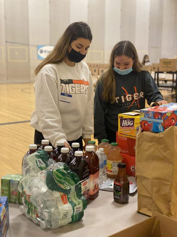 Laughing+together%2C+junior+Keegan+Weddle+and+sophomore+Allison+Mowery+sort+food.+On+Dec.+20%2C+the+varsity+girls+basketball+team+volunteered+with+the+Kiwanis+Club+helping+prepare+food+baskets+for+people+in+need+over+the+holidays.