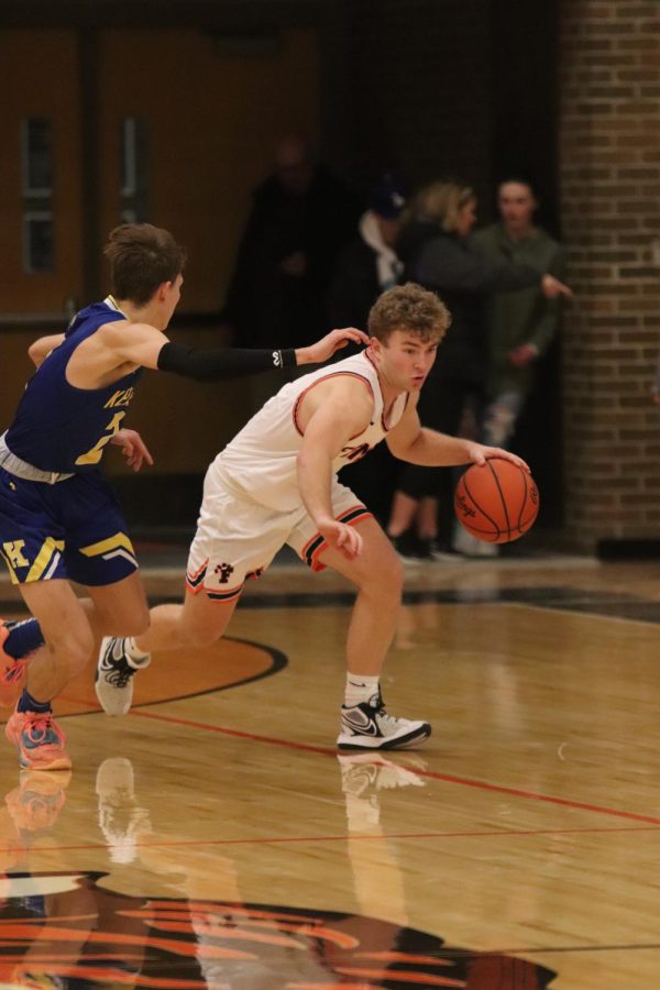 Pushing up the floor, senior Connor Luck dribbles the ball past his defender during the varsity boys basketball game against the Kearsley Hornets. On Jan. 7, the Tigers played the Hornets and won 68-61.