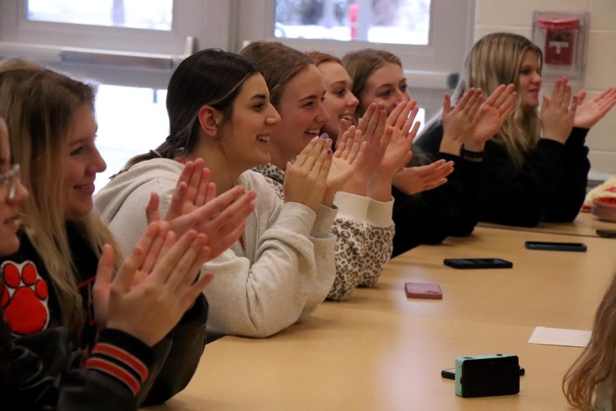 Clapping, junior Keegan Weddle smiles alongside her teammates. On Feb. 10, the girls varsity basketball team celebrated their teammate, senior Kaleigh Shaker, at her signing to play college basketball at Aquinas. 