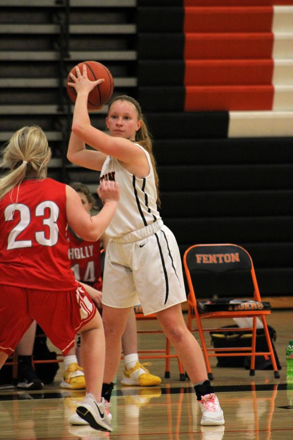 Looking for a open pass, sophomore Nina Frost looks over the court. On March 1, the JV girls basketball team faced Holly for their last game of the season winning 46-8.