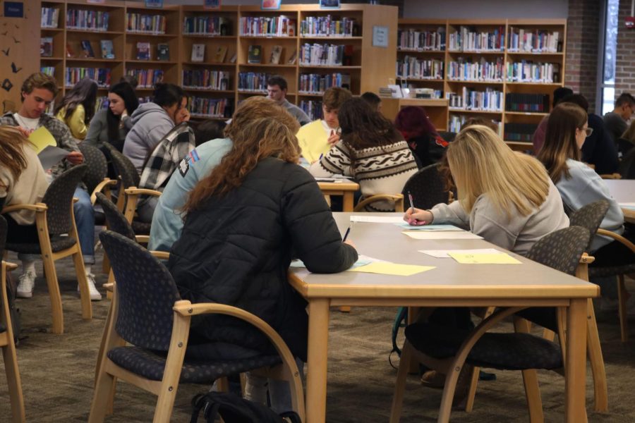 Jotting down notes, Senior Dylyn Nichols along with her fellow classmates attend an informational meeting.  On April 19, all IB and AP students attended a meeting about IB/AP testing in the media center.  