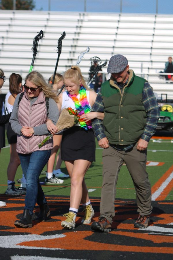 Senior Emma Horne is escorted across the field by her parents. On March 4, FHS put together a ceremony to honor all senior girls on the varsity lacrosse team. 