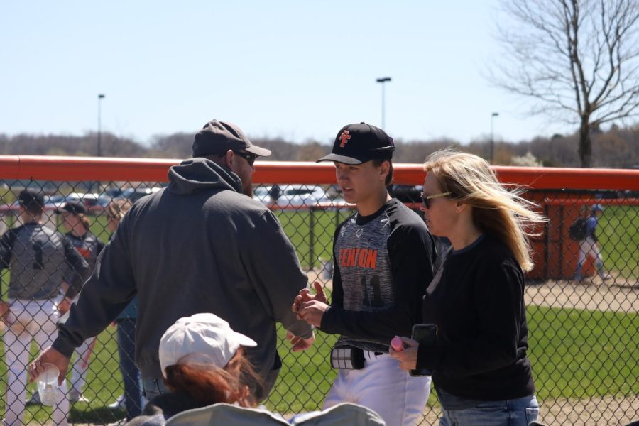 On his way to join the team picture, junior Zach Brown talks to his mom in between games. On May 7, the varsity baseball team hosted the annual woodbat tournament and presented pink, wooden bats to their mothers for Mothers Day.