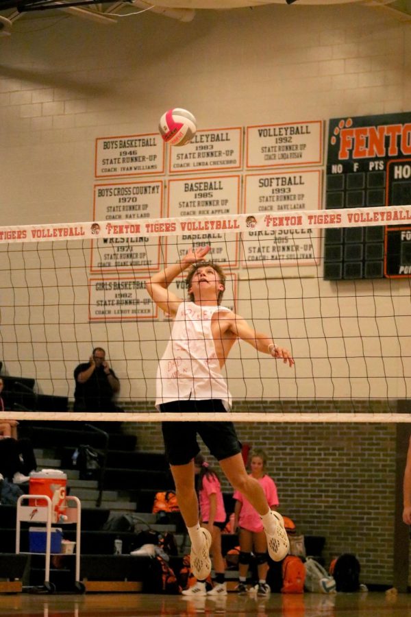 Jumping in the air, senior William Dickens spikes the volleyball. On Sept. 20, the boys soccer program played a friendly volleyball match against the girls volleyball program to raise funds for a local cancer patient. 