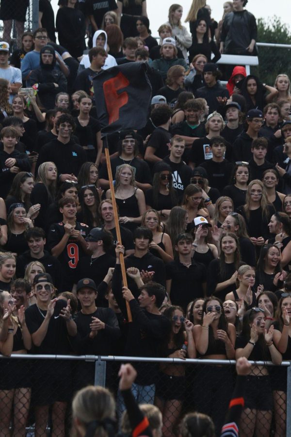 Waving+the+flag%2C+the+FHS+sudent+section+dresses+in+black+to+support+the+Fenton+varsity+Tigers.+The+Fenton+Tigers+went+up+against+Midland+Dow+on+Aug.+25+and+won+46-7.+