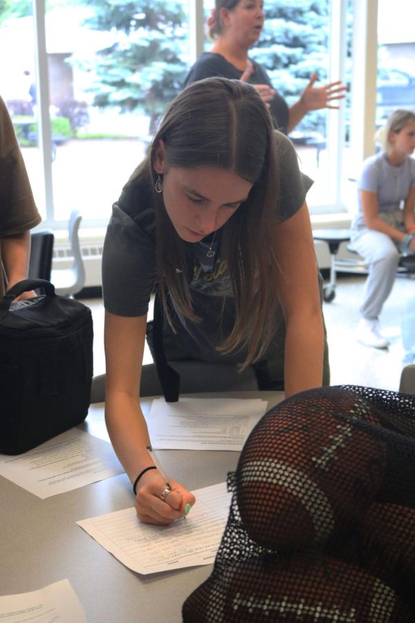 At the senior powderpuff meeting, senior Lillia Pihlstrom signs the contact information form. On Sep. 6, the seniors met in the cafeteria to discuss information about the powderpuff game that will take place on Sep. 26.