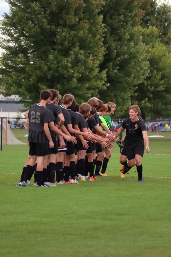 Running through the lineup, senior Leo Thompson high-fives his teammates. On Sep. 12, the varsity Tigers were victorious over the Owosso Trojans with a score of 3-0. 