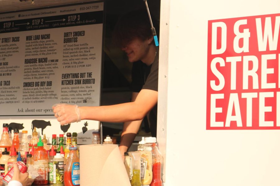 Handing off a Coke, senior Dylan Klassen serves a customer for D&Ws Street Eatery. On Sept. 16, D&Ws Street Eatery was one of the first food trucks to make an appearance at Applefest. 