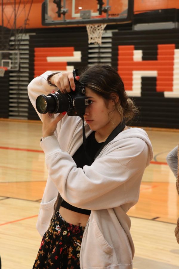 Taking practice shots, sophomore Ava Slezinski aims her camera. On Oct. 12, members of the Fentonian yearbook staff went around and took practice shots in the FHS gym.  