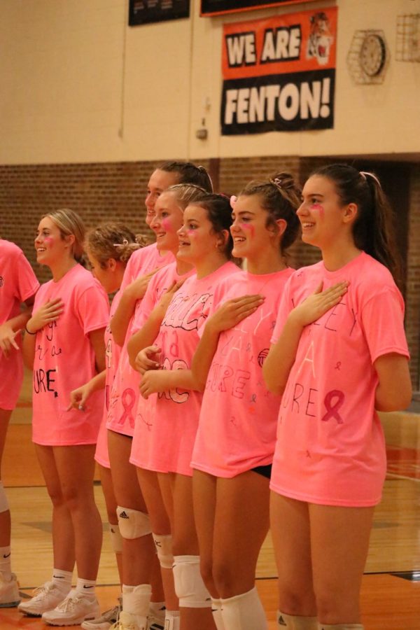 Hand over their heart, members of the varsity volleyball team sing the national anthem. On Sept. 20, the volleyball program played a game of volleyball against the soccer program in order to raise money for a cancer recipient. 