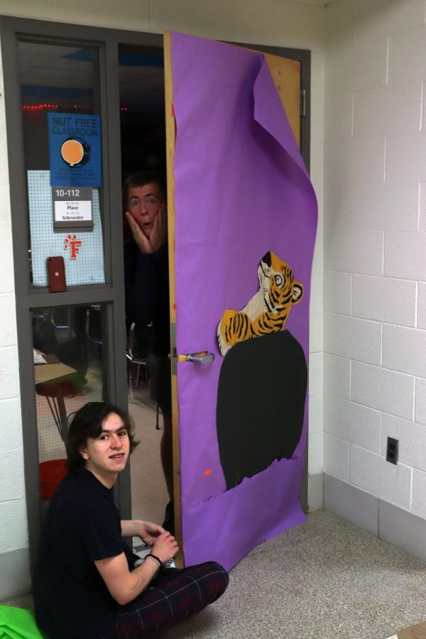 Participating in FHSs Halloween spirit door decorating competition, seniors John Dixner and Will Hansard decorate teacher Matt Places door. On Oct. 18. many classrooms had students decorating doors to compete to win the SRT competition. 
