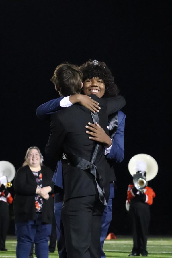 Accepting his crown, senior Ibrahim Sene hugs former FHS student and homecoming king Chase Gibson. During the Fenton v. Kearsley halftime performance on Sept. 30, the new homecoming king and queen were announced and crowned on the field.
