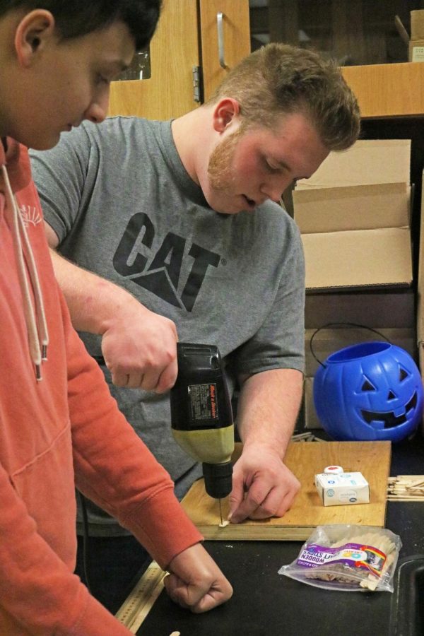 Drilling through a popsicle stick, senior Garrett DeWitt works on a project. On Oct. 12, FHS teacher Jason Kasaks physics class continued working on the popsicle stick bridge project. 