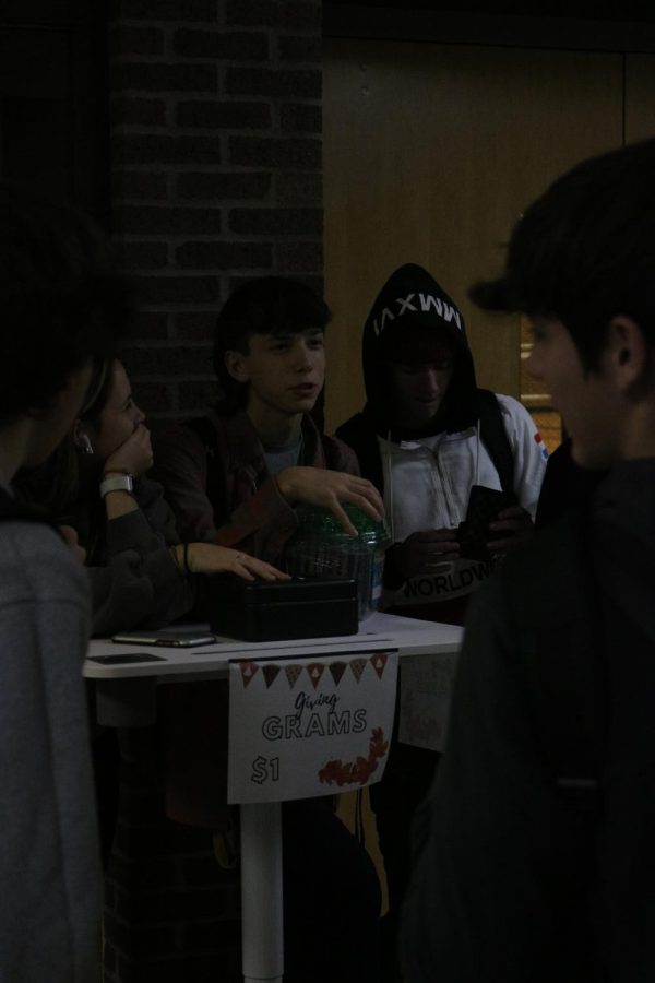 Selling giving grams in the square, junior Alex Wire chats with his classmates. On Nov. 18, the Fentonian staff members sold giving grams during lunch by the cafeteria. 