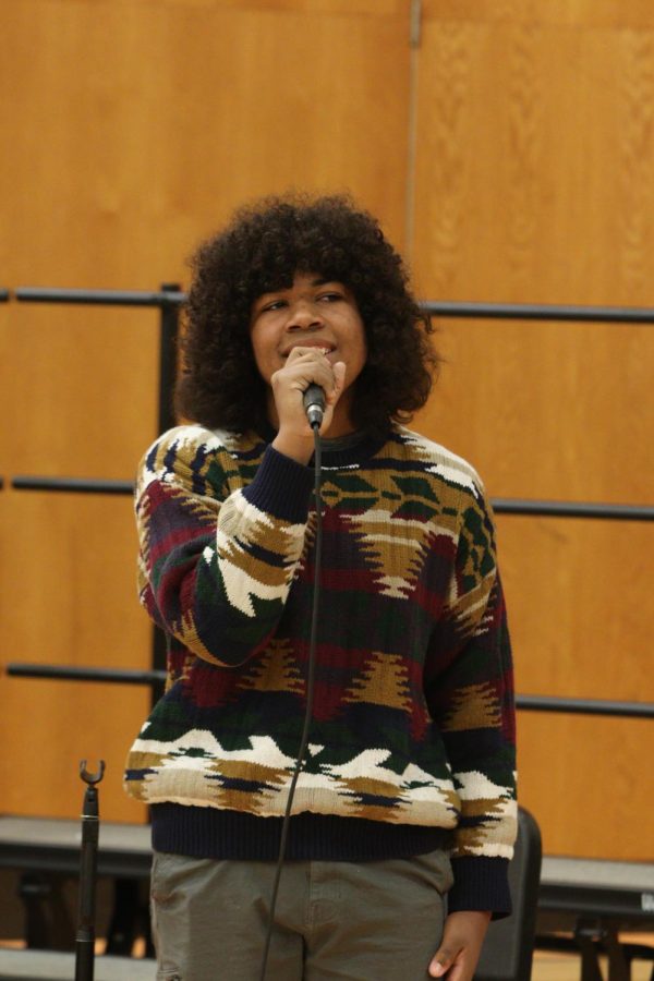 Gazing at  the crowd, senior Ibrahim Sene sings to the audience. On Dec. 15 the choir and band puts on  Christmas concert during SRT. 