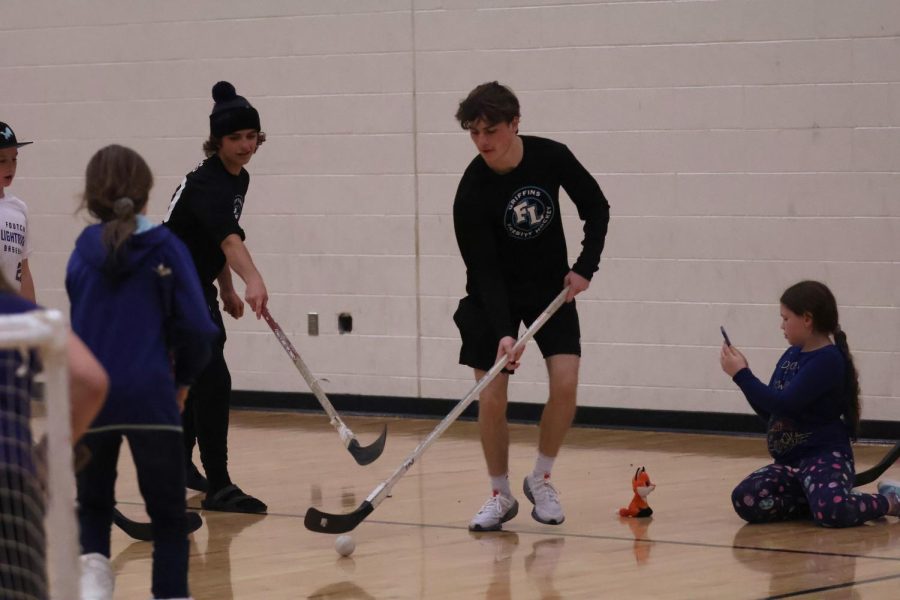Dribbling the ball, senior Mitchell Luck is playing with the kids. On Nov. 18, the Griffins hosted a hockey lock-in to raise money for their program. 