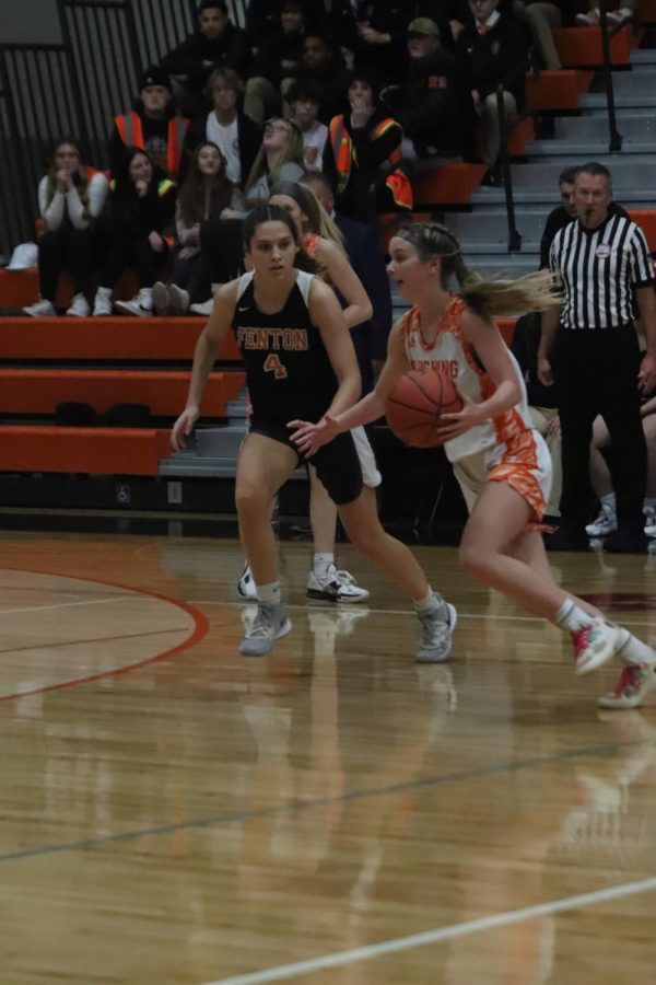 Following her apponent, senior Madison Slezinski watches the ball. On January 3, the Fenton varsity baketball team plays against the Flushing team and lost 32-53