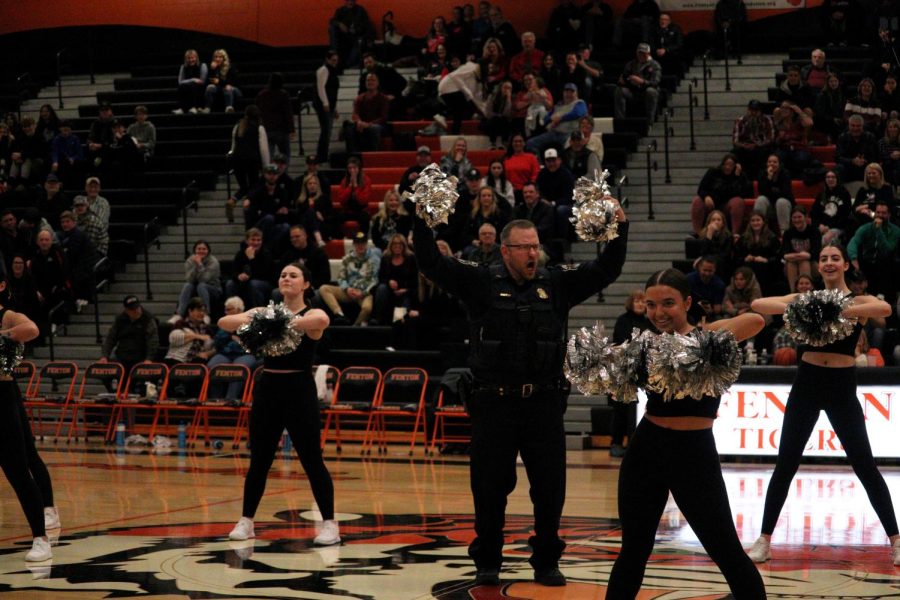 Hands in the air, Fenton Area Public Schools Resource Officer Tom Cole hypes up the crowd. On Feb. 17, the FHS Dance Team performed a special dance performance at halftime of the boys varsity basketball game with Officer Cole. 