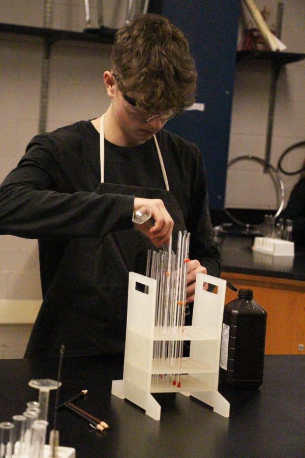 Collecting a thermometer, sophomore Aaron Brown participates in an enzyme lab. On Feb. 13 Biology classes tested reactants of enzymes by using a deer heart. 