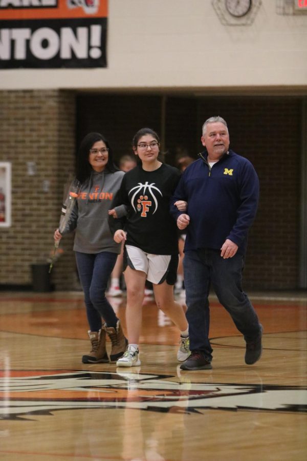 Walking the court with her parents, junior Naomi Durant looks to the audience. On Jan. 30, FHS held parents night before their game aginst Clio. 
