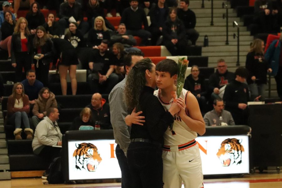 Hugging his mom, senior Coiln TerBurgh presents her with a flower. On Feb. 17, the boys varsity basketball team hosted a senior night honoring the seniors and their parents. 