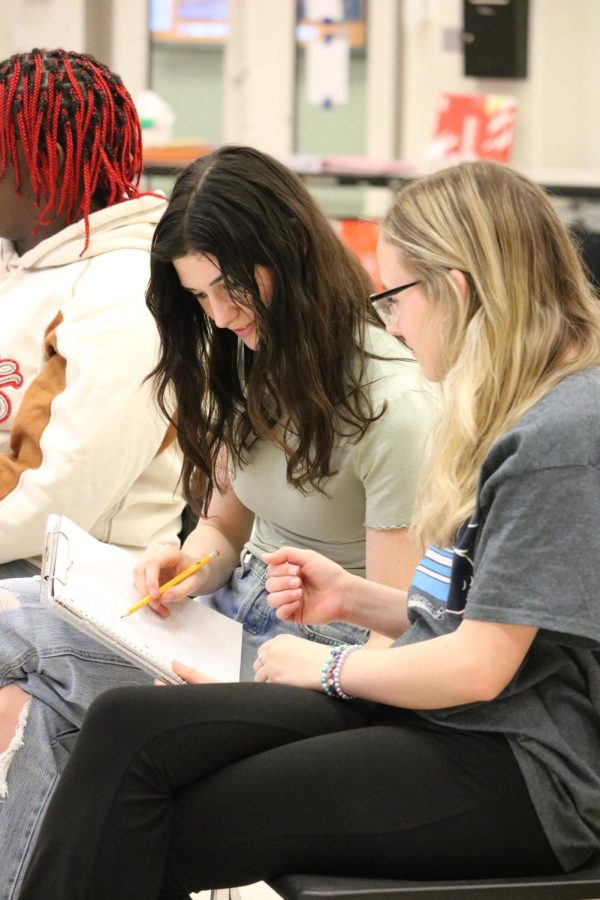 Looking at the paper, juniors Brooke Severn and Danielle Weaver sign up for color guard. On April 13, there was an informational meeting regarding color guard for the 2023-24 school year.