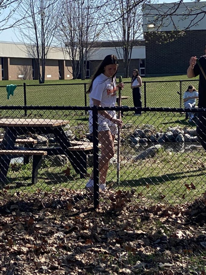 Raking the leaves, senior Allie Lutz helps clean up the pond. On April 13, members of FHS teacher Matthew Sullivans forensics class helped clean up the pond. 