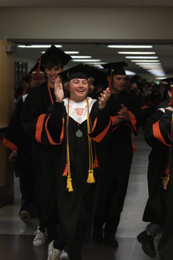 Walking with a smile on his face, senior Adam Barcome claps as the seniors walk through the FHS hallways on their way to the football field. On May 25, Fenton High School held a senior walk where all the seniors walked through the school then to the football field. 