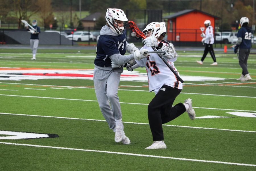 Handling the ball, freshman Nate Fuller attempts to run past his defender. On May 2, the Fenton Boys varsity lacrosse team competed against Goodrich; losing 8-9. 