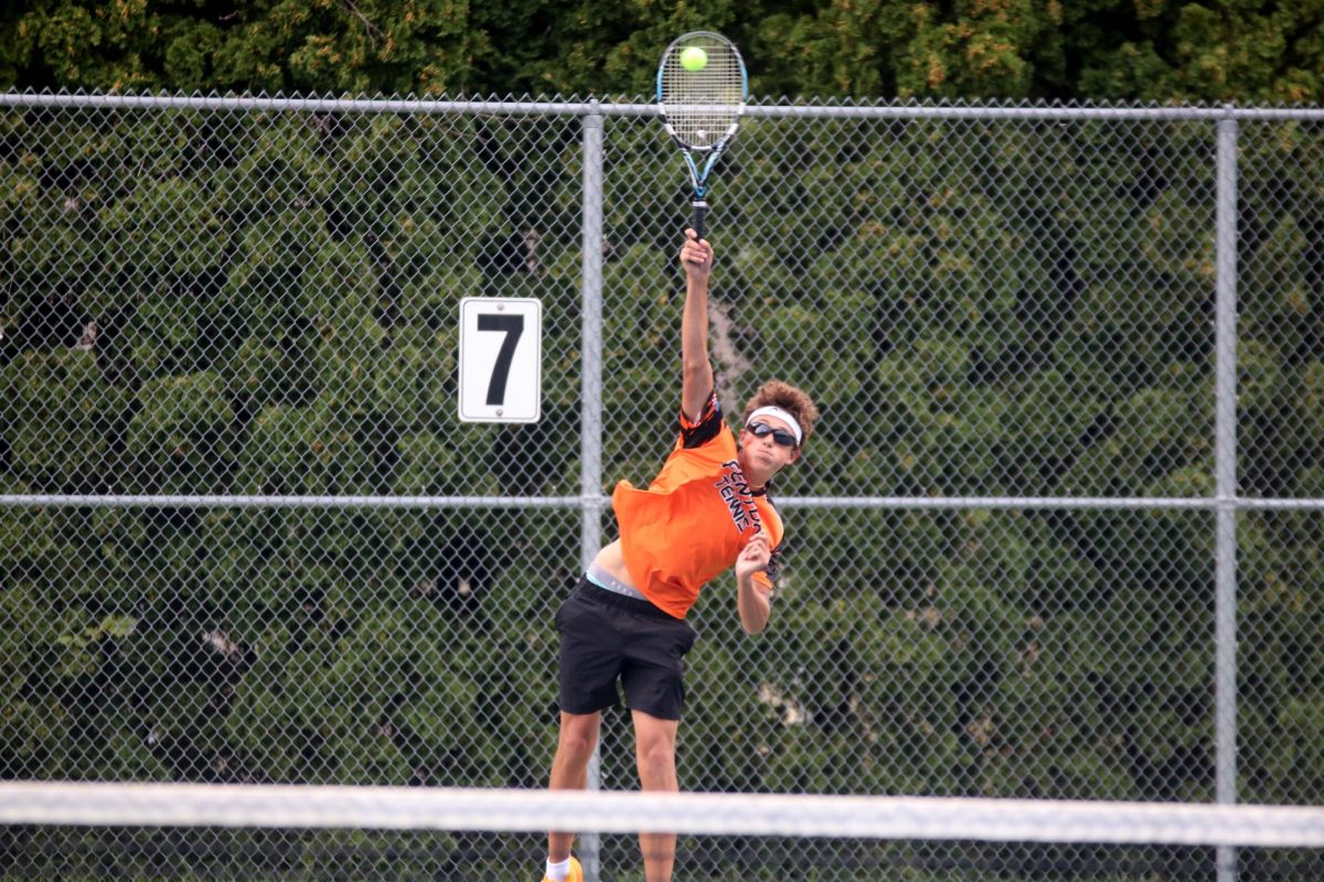 Hitting the ball with his racket, junior Kalib Matthys serves to his opponent. On Sept. 12, the Fenton boys varsity tennis team went up against Clio and lost 1-7.