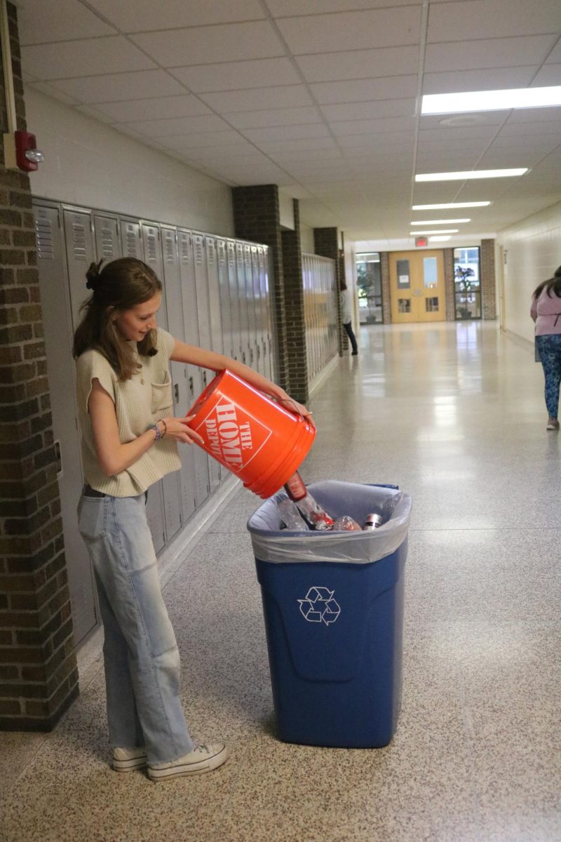 Dumping used cans into a bin, Senior Lauren Janowak is doing her weekly SRT duties. On Sept. 14 the Fenton Eco Club went around to each classroom to get all the recycled bottles. 