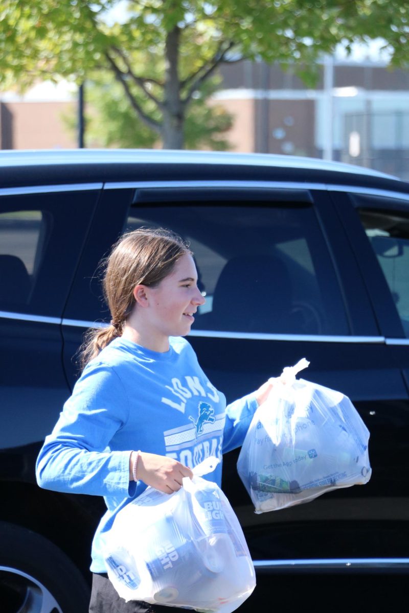 Collecting bottles Freshman Ava Arntz helps raise money for the class of 2027. On Sept. 24 the bottle drive occured in the Fenton high schools parking lot.