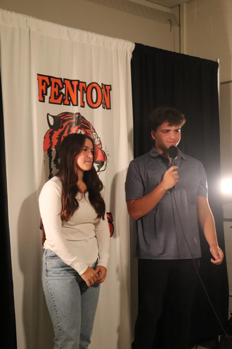 Standing in front of the camera, senior Sara Kanaski answers interview questions with senior Carson Krzeszak. On Sept. 28, members of the homecoming court were interviewed for FHS News.