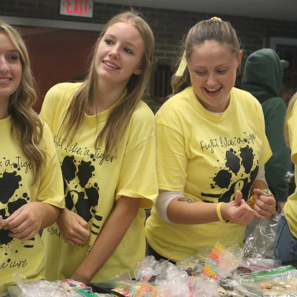 The varsity volleyball team at their bake sale to help fight childhood cancer. Senior Makenzie Lawson and sophomore Marley Pihlstrom are seen happily helping out their team.