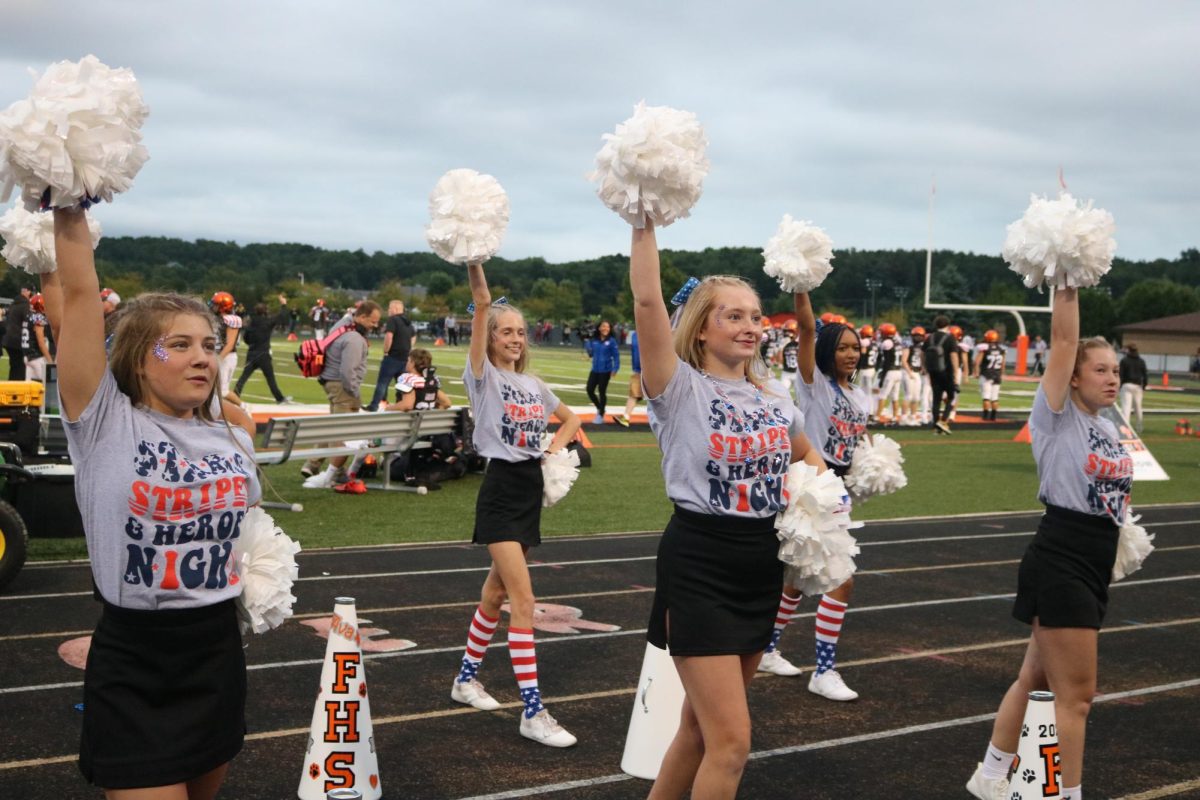 Cheering against Swartz Creek, the varsity cheer team, helps increase crowd participation. On Sept. 8, the varsity cheer team cheered against Swartz Creek High.