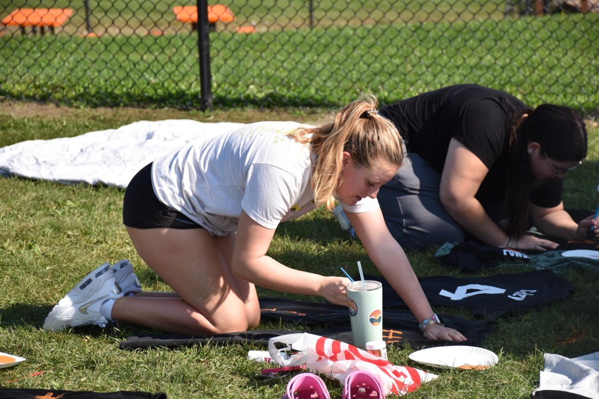 Kneeling down, senior Charlotte Perez paints her uniform. On Oct. 1, the seniors had their last practice for the powderpuff game.