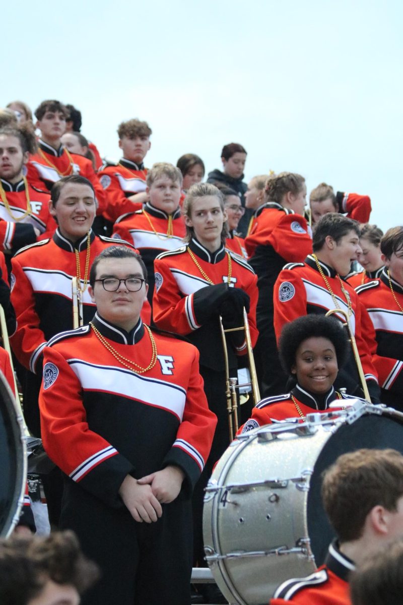 Playing for Varsity football, the Fenton Marching Band observes the game. Marching band also wore gold beads in honor of childhood cancer. 