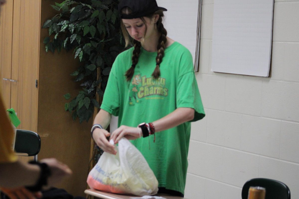 Tying up plastic bags, freshman kayla mccloy is prepping shirts to be distributed to classrooms for color wars on 10/5. 