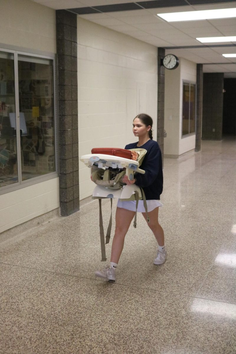 Walking to class, sophomore Kennedy Walrath participates in Anything but a Backpack Day. On Oct. 10, Kennedy brought a high chair and carried it with her throughout the day.