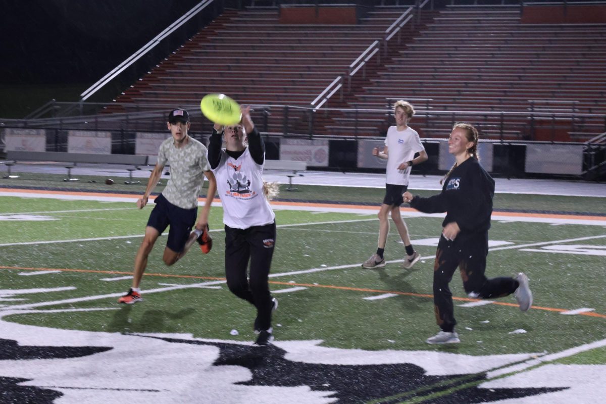 Catching the frisbee, sophomore Reese Canada participates in an ultimate frisbee game. On Oct. 4, the cross country team spent the night on the football field.