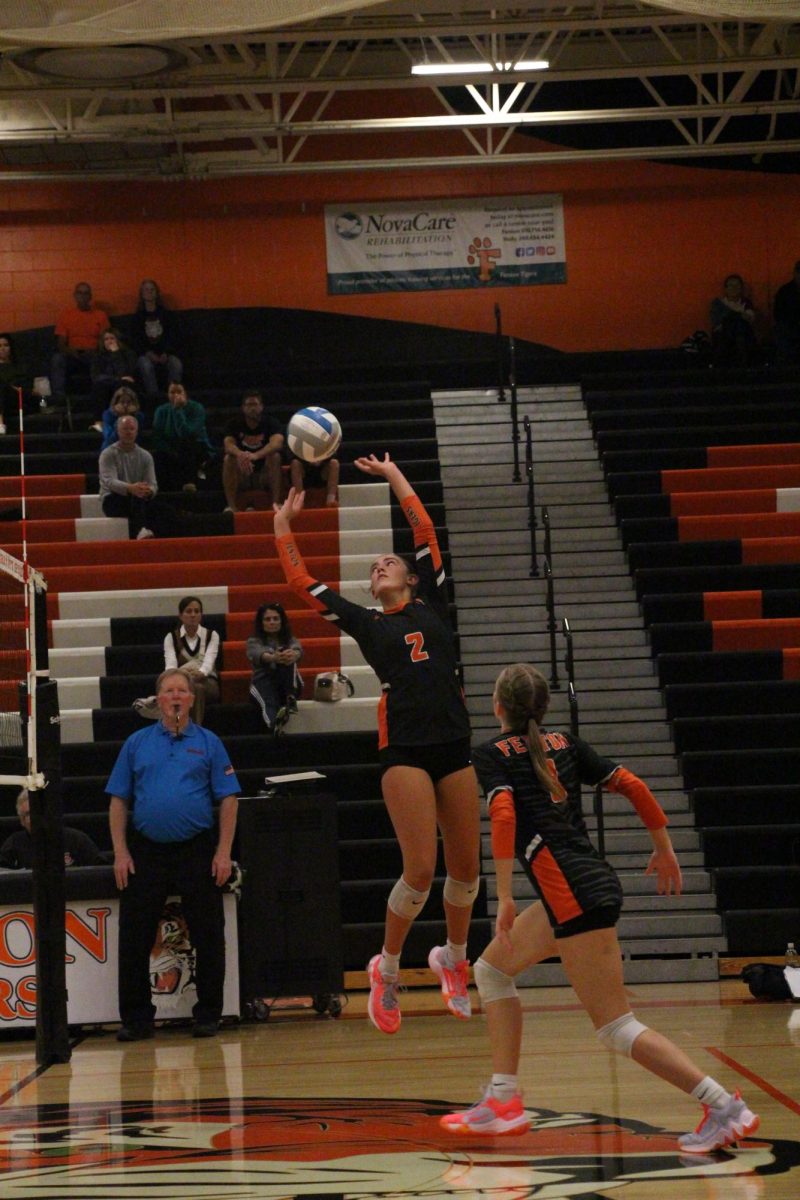 Setting the ball, sophomore Eva Long jumps into the air. On Sept. 27, the varsity volleyball team competed against Flushing, winning 3-0. 