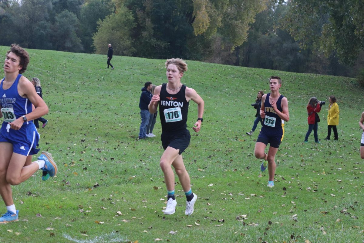 Running, freshman Ben Marx competes against other Flint Metro League teams to place in the championship jamboree. On Oct. 18, the varsity cross country team had their final league meet of the season.