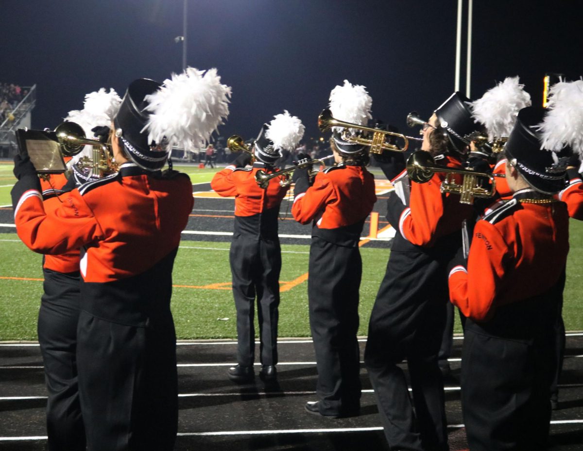 Playing on the track, the FHS marching band plays for the childhood cancer awareness football game. On Sept. 29, the marching band wore gold beaded necklaces to show support for childhood cancer during halftime.