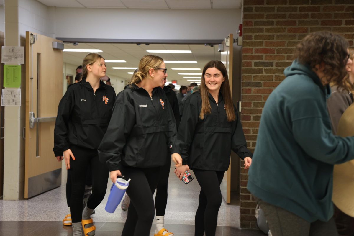 Laughing, juniors Addison Dolliver and Tess Heavner walk their way out of school on their way to states. On Nov. 16, Fenton high school held a clap out for the girls swim team.