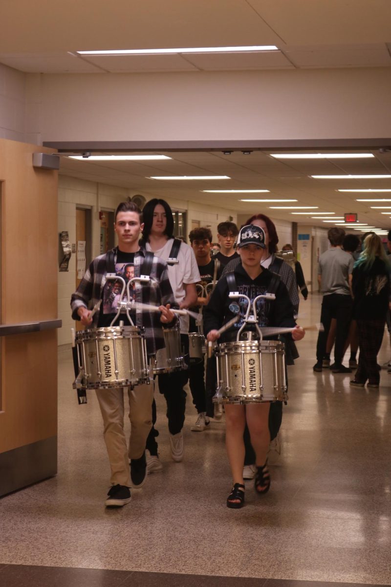 Drumming, sophomore Joe Wright along with fellow classmates play music to lead the swim team to states. On Nov. 16, the swim team walked out with the drum line to celebrate making it to states.